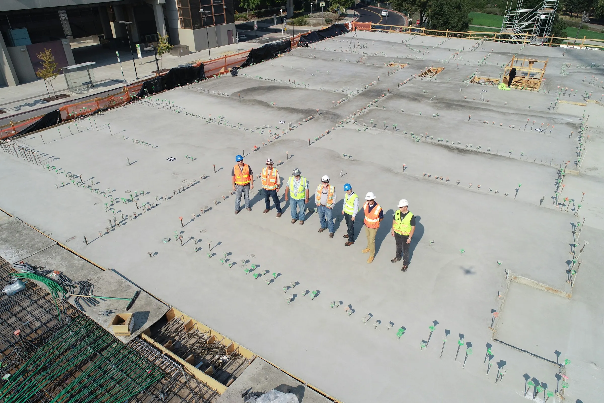 A construction crew standing in a line on a freshly finished concrete slab, seen from above